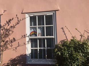 A child's picture of a rainbow placed on the inside of a window so it is visible to people passing by