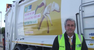 Cllr Brian Milnes standing in front of a bin lorry.