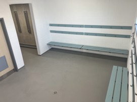 One of the changing rooms inside the Northstowe Western Park Pavilion. There are benches to sit on and pegs to hang clothing on.