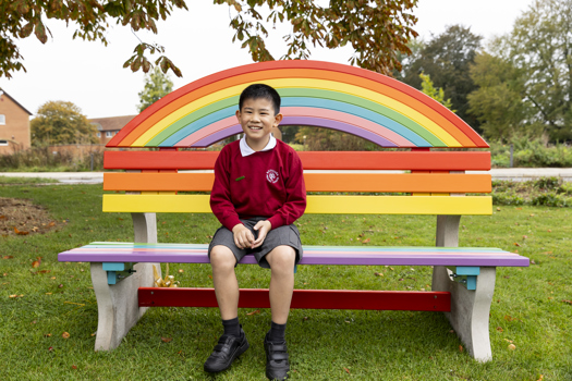 A Melbourn student sits on his rainbow bench at the Science Park