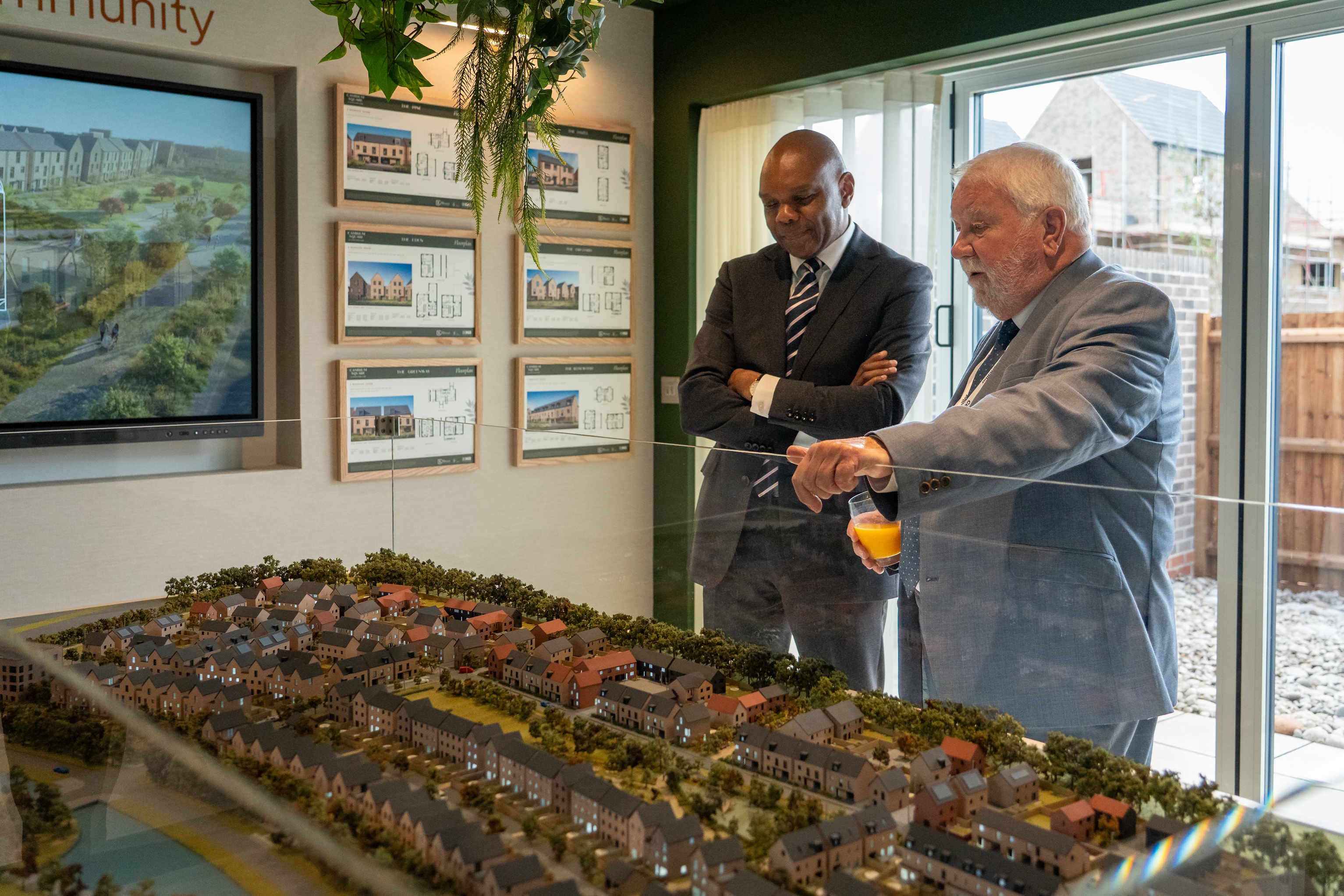 Two people view a scale model of the Cambium Square development inside the sales suite, with plans and images of the new homes displayed on the walls behind them.